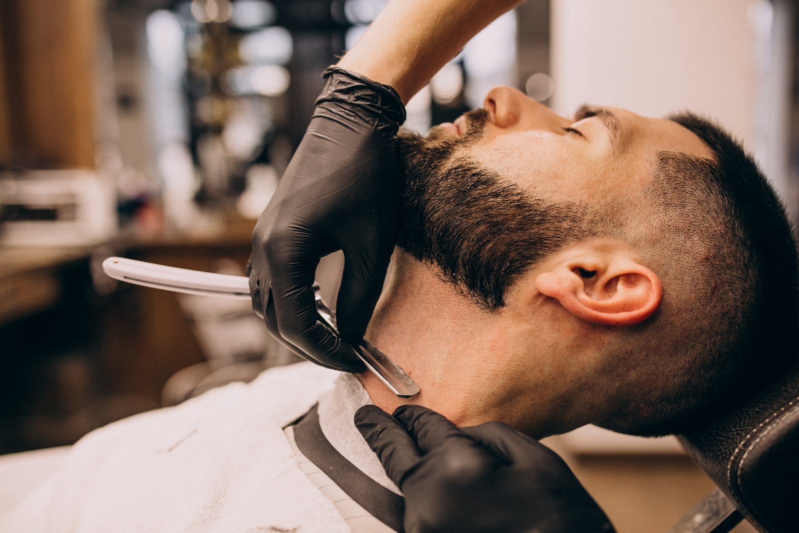 Barbeiro fazendo acabamento de barba na navalha em cliente masculino