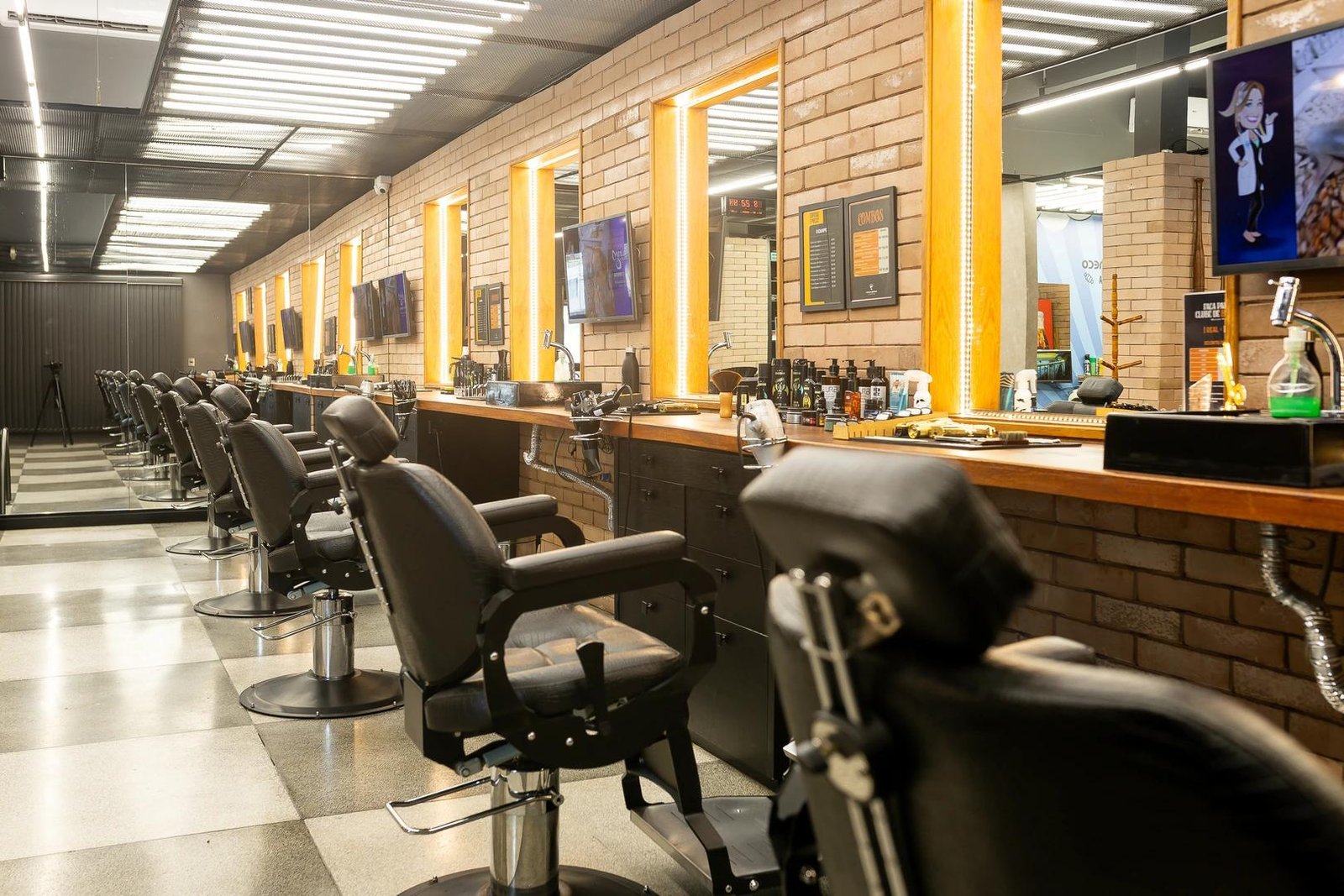 Interior da barbearia em Joinville com cadeiras de barbeiro e espelhos iluminados